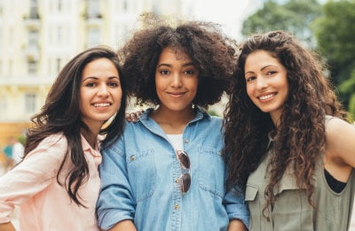 Three young multi-ethnic women standing in a courtyard. Lupus affects more women than men.