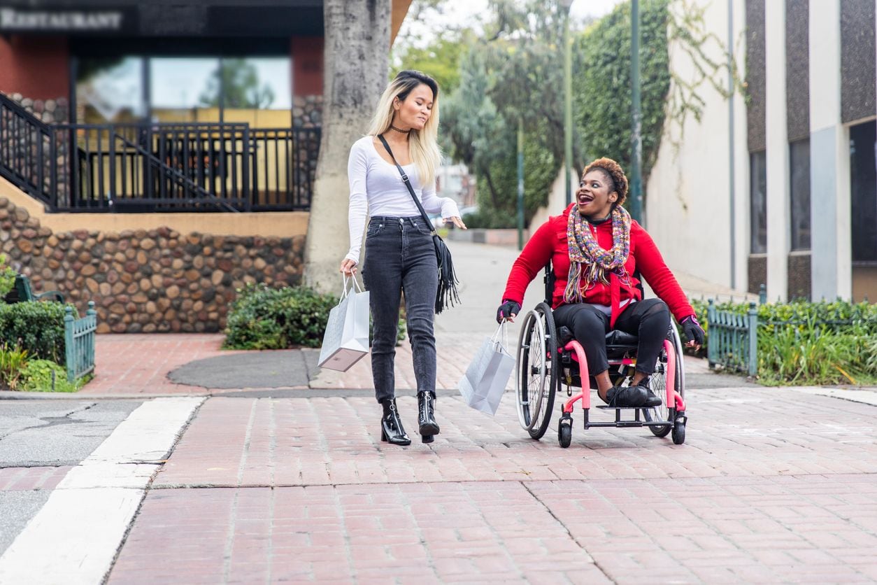AA woman in wheelchair on a walk with a friend