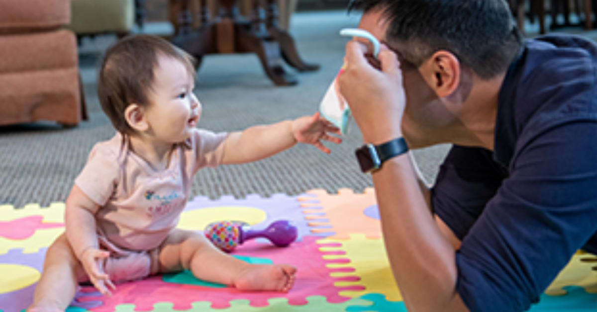 Dad playing peek-a-boo with baby.