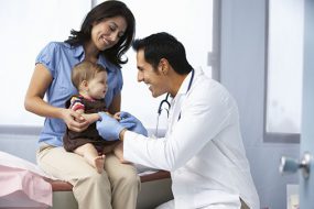 A mother holds her child on her lap while talking to a healthcare provider