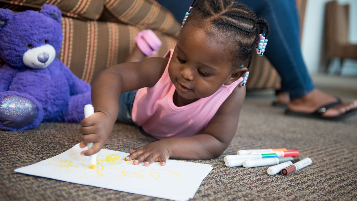 child scribbling with marker