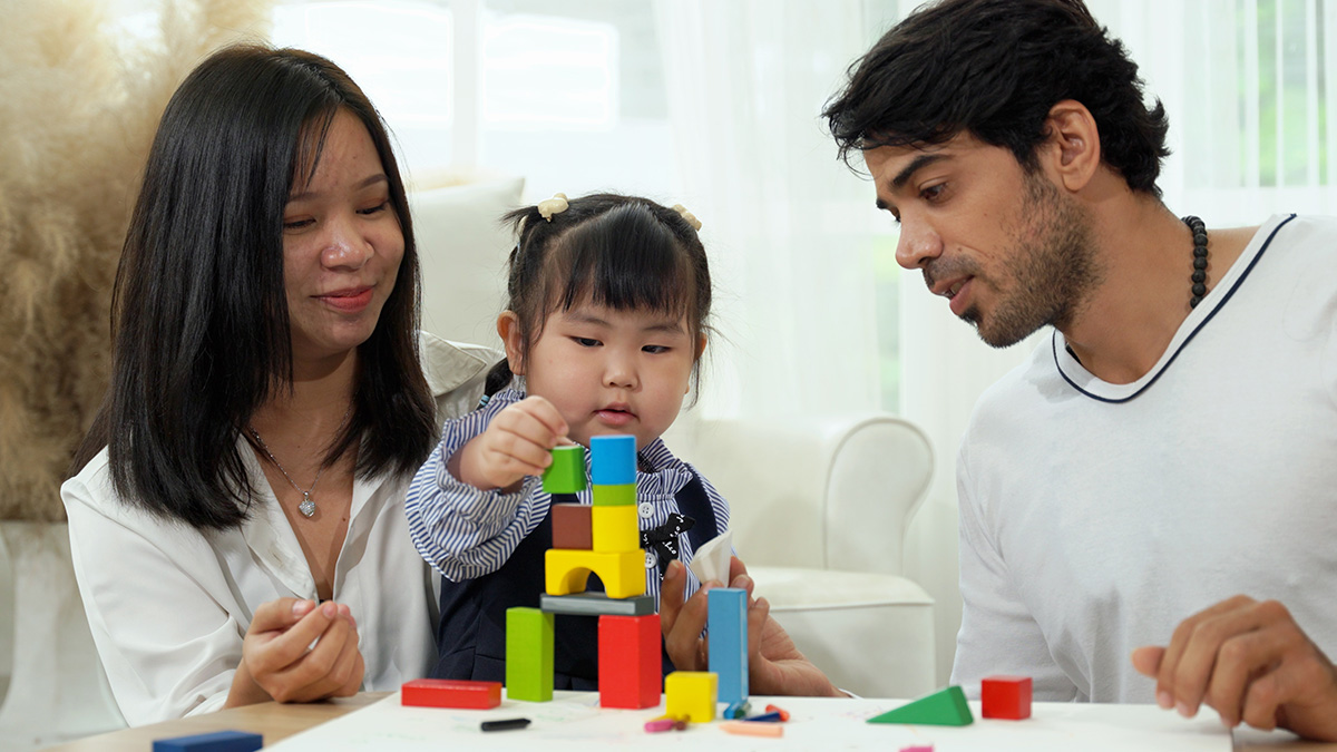 Parents play with blocks with their child.