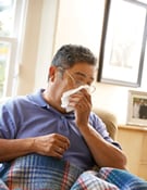 Coughing can help clear congestion when you are sick with the flu. Cover your cough with a tissue, like this man.