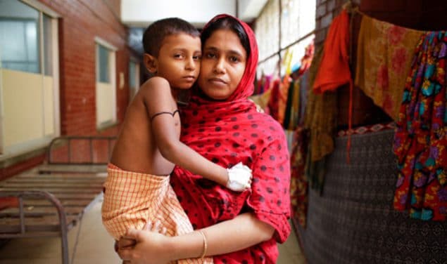 A woman holds young boy recovering from typhoid fever at a healthcare facility in Bangladesh, 2016.