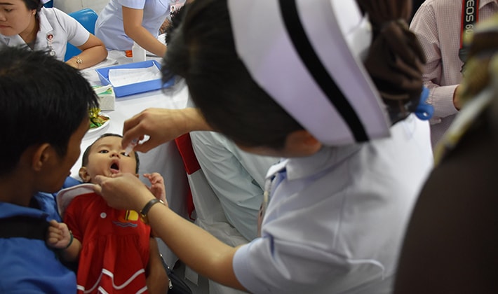 In the second picture shows a child is being vaccinated with OPV at the official STOP ISDS Lao PDR pilot launch ceremony.
