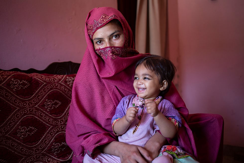 A mother in Pakistan brings her young daughter to get a second dose of measles vaccine along with other routine vaccines.