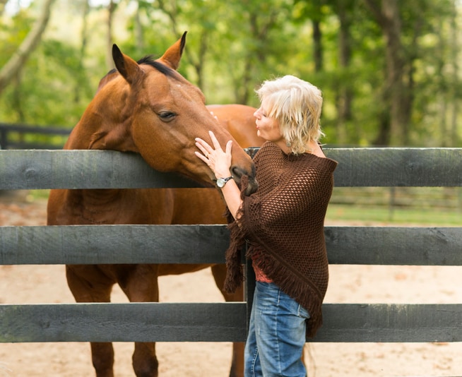Blonde woman touches thoroughbred horse
