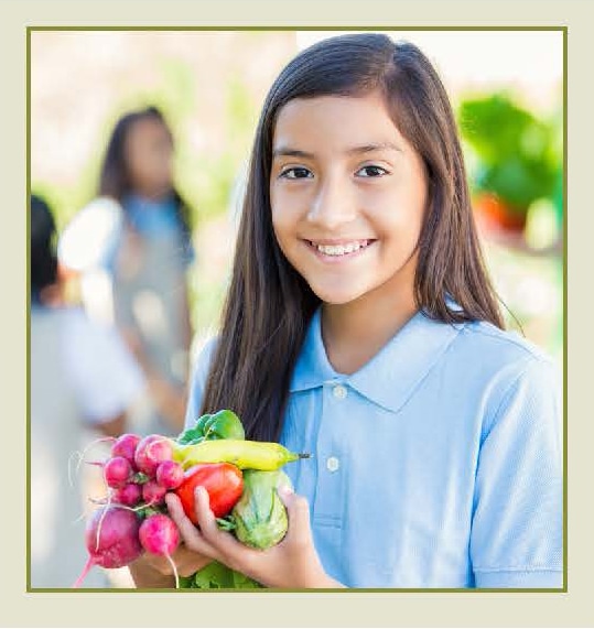 girl smiling holding fresh picked vegetables