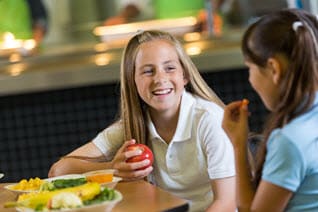 Dos estudiantes disfrutan su almuerzo en el comedor escolar.