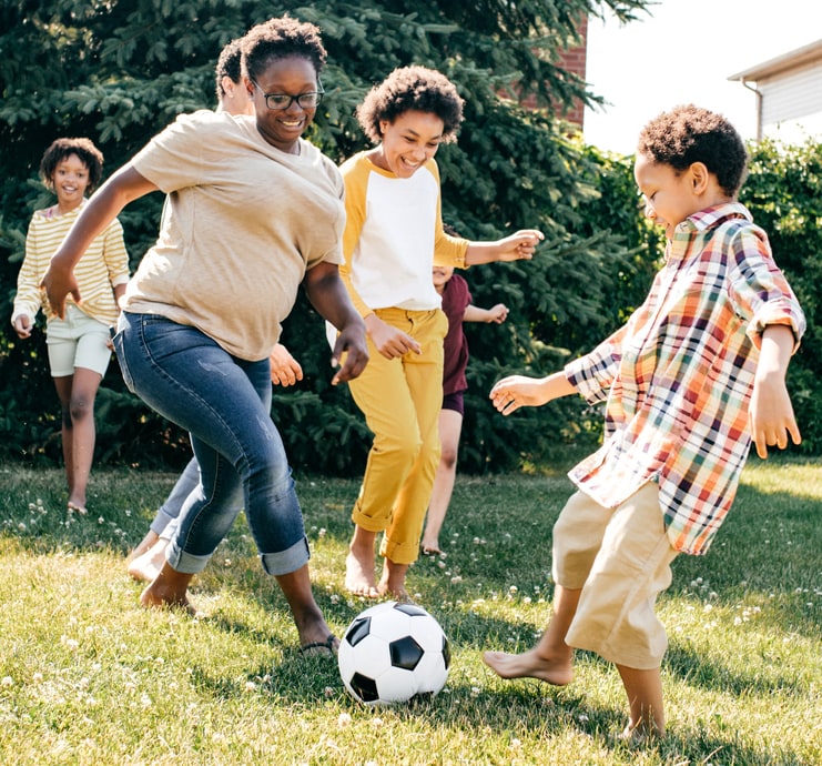 Teens playing a friendly game of soccer in a yard.