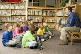 Foto de un adulto leyéndole a un grupo de niños