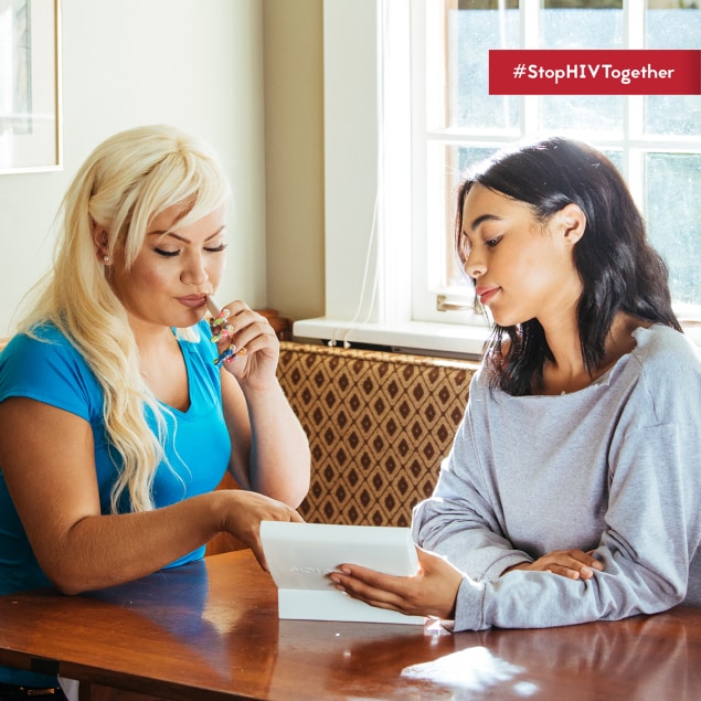 Two people sit at a table. One is taking an HIV self test. Both are looking at the self-test instructions. Text says #StopHIVTogether.