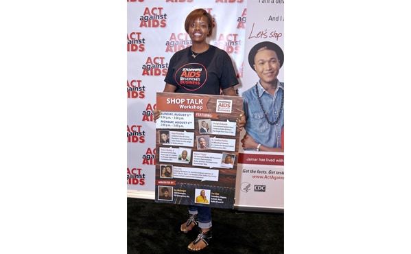 Nancy McCreary, hair show volunteer, holds a sign to promote HIV awareness, prevention, and education at the Shop Talk Workshop
