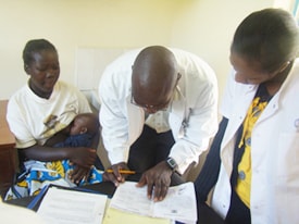 KEMRI Clinical Officer Paul Ogai reviews a prospective participant's vaccination card during trial enrollment at the KEMRI/CDC site in Kenya. (Alan Rubin, KEMRI)
