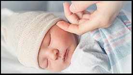 The figure shows a mother’s hand comforting a sleeping newborn infant.