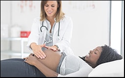 The figure shows a pregnant woman lying down and a female doctor examining her abdomen.