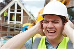 The figure above is a photograph showing a construction worker reacting negatively to loud noises.