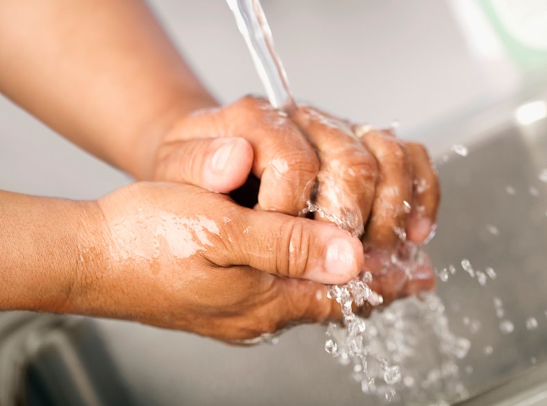 A person washing their hands under running water.