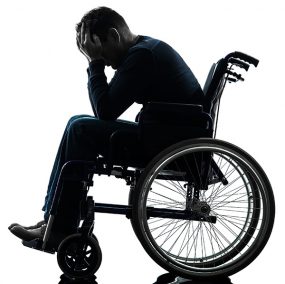 Man sitting in a wheelchair with his head in his hands