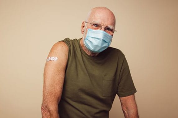 Man wearing mask with bandage after getting a vaccination.
