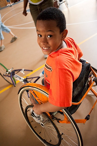 A boy with spina bifida smiles in his wheelchair