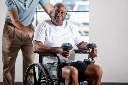 a senior man in a wheel chair training with weights