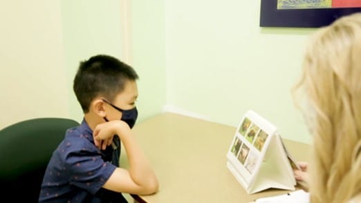 Child working on a language and communication activity with a teacher