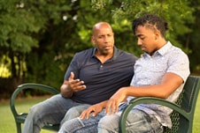 An African-American father sitting with his son
