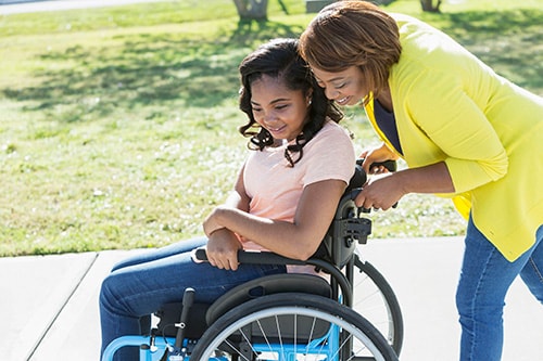 A woman pushing another lady who is in a wheelchair