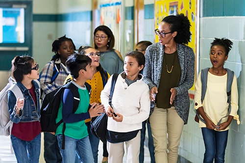 Multiracial teacher and children in school hallway