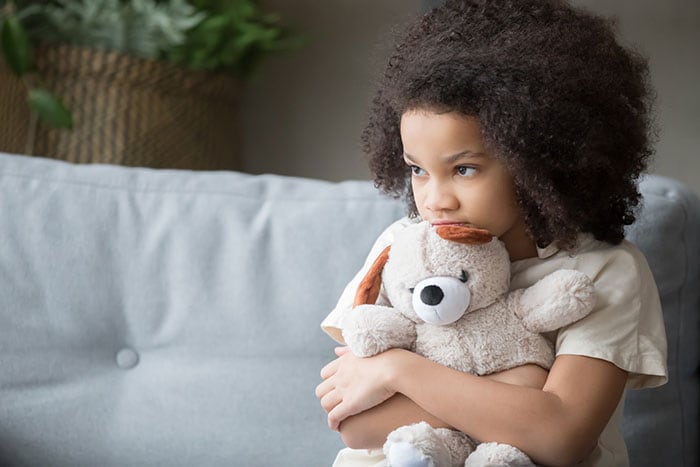Upset lonely african girl holding teddy bear looking away