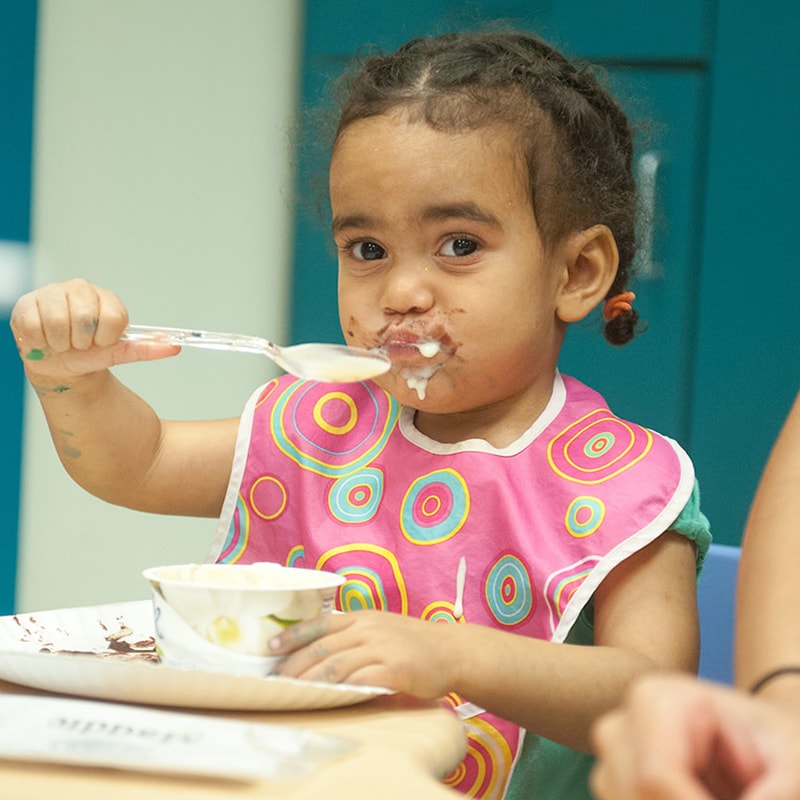 Una niña come con una cuchara.