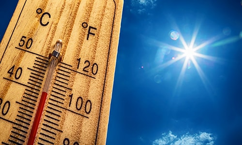 a thermometer showing over 100 degree fahrenheit against a bright sunny sky