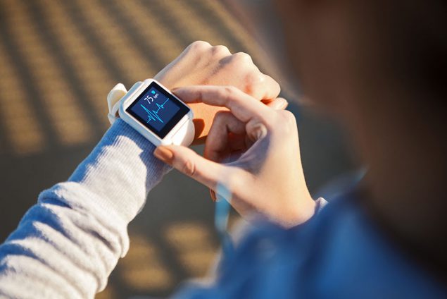 Young Active Woman Using Exercise Tracking App On Smartwatch