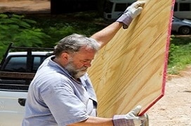 men caring a large panel of plywood
