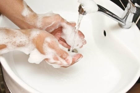 Woman washing her hands with soap and water in a sink.