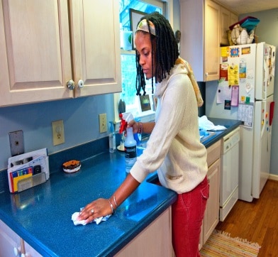 Woman cleaning kitchen counter at home.