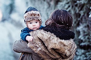 Alaska Native mother carrying her infant son outside in a wintry wonderland