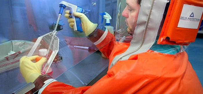 A laboratorian is shown working in a high-security lab wearing an air-tight, self-contained, positively-pressurized suit, which keeps him free of possible contamination while he carries out his experiments.