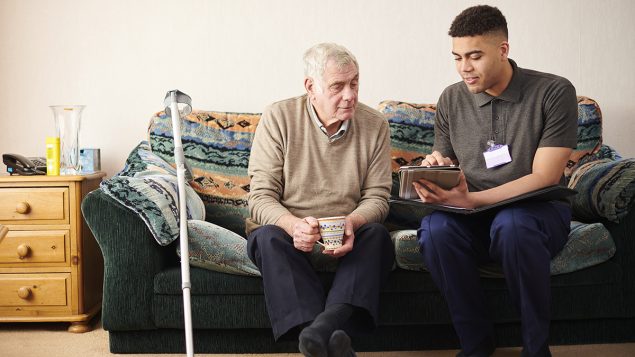 Young man and older man on a couch looking at a clipboard