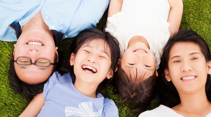 Family lying on grass and smiling