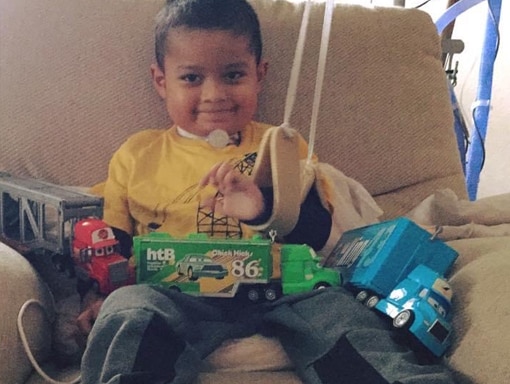 Francisco smiling with his toys in his lap.