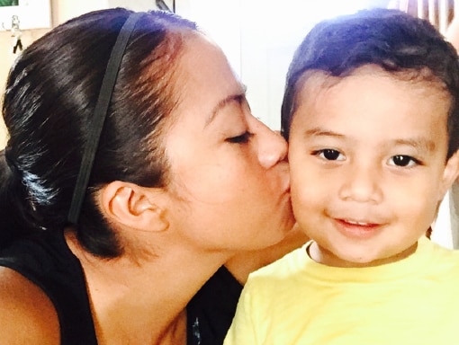 Francisco receiving a kiss from his mom.