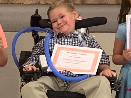 Jack in his wheelchair with his physical therapy certificate.