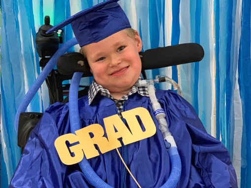 Jack smiling in his wheelchair at his graduation.