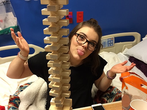 Sarah making a silly face behind a tall Jenga tower