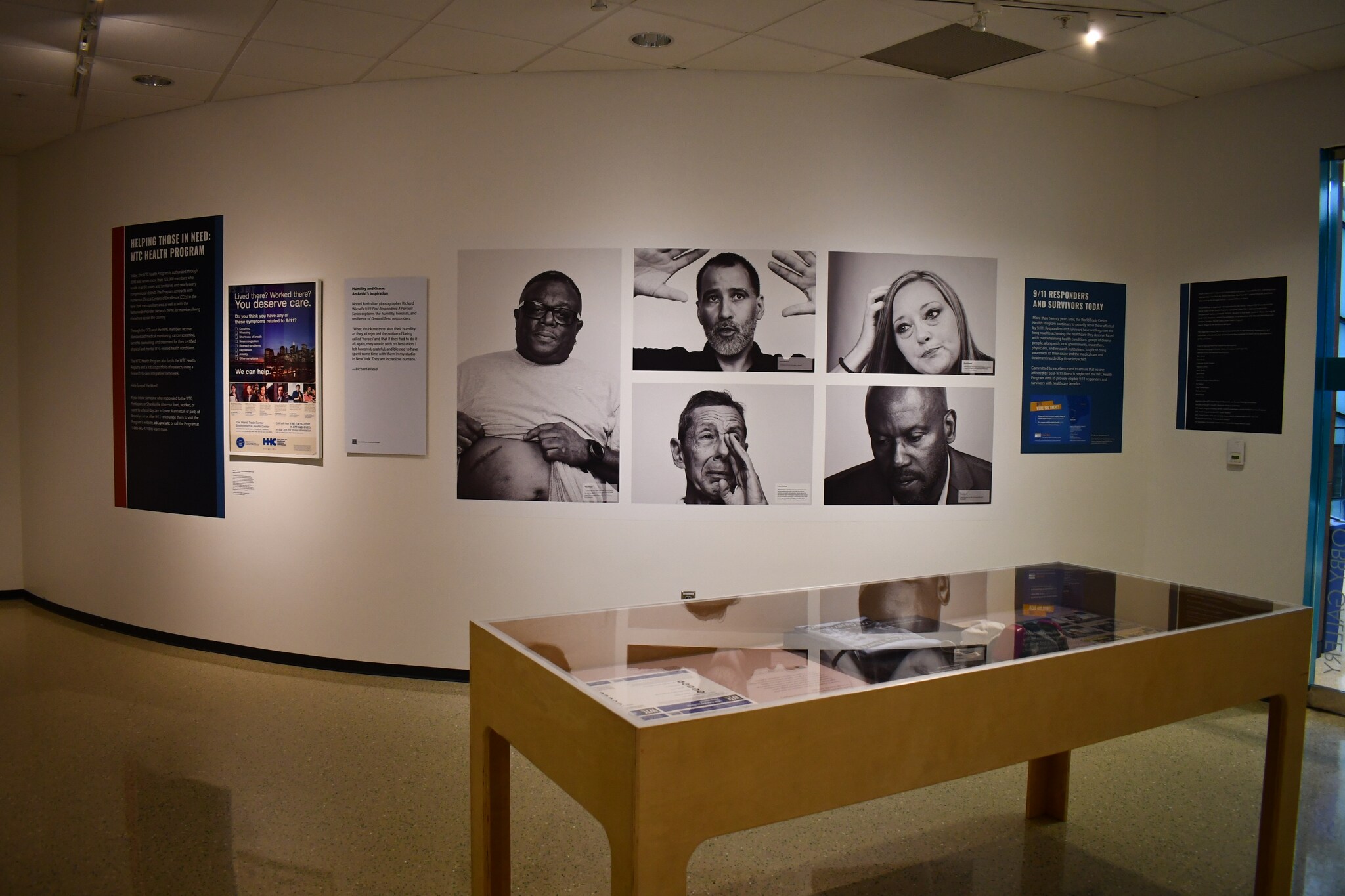 A wall displaying various artifacts and images of survivors from the Health Effects of 9/11 Exhibition.