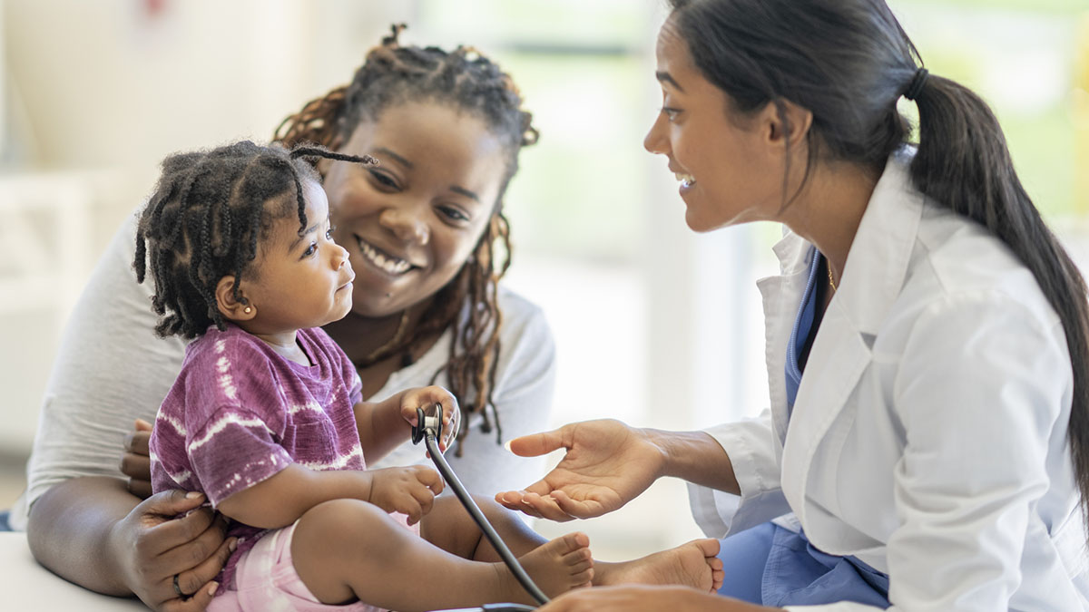 Healthcare provider talks with mother and her son in a doctor's office.