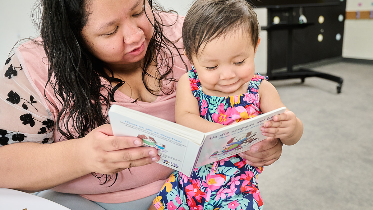 mom holding baby on lap and reading a book