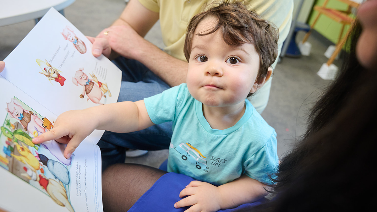 Two year old points to an image in a picture book.